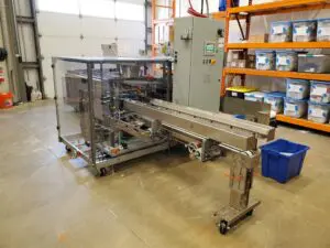 A machine in a warehouse with boxes on the floor.